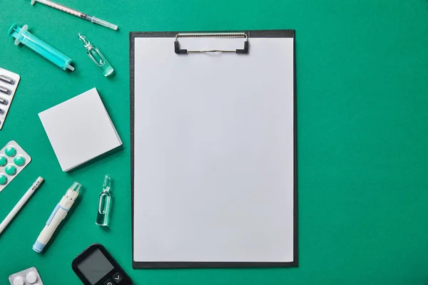 Top view of various medical supplies near folder and on green surface — Stock Photo