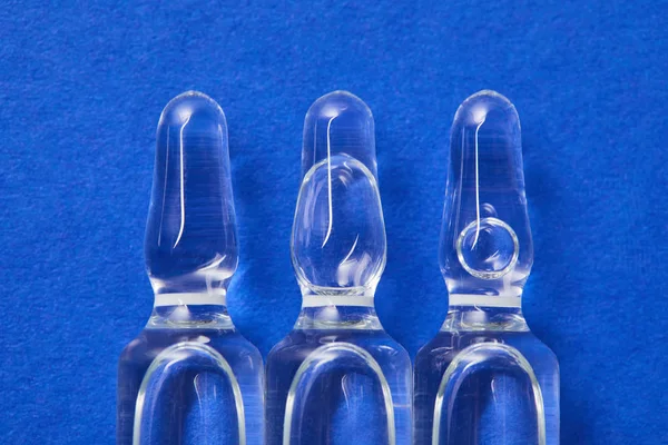 Vista de cerca de pocas ampollas con líquido de tambor en la superficie azul - foto de stock