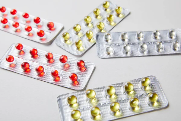 Розсіяні блістерні пакети з барвистими прозорими таблетками ізольовані в білому — стокове фото