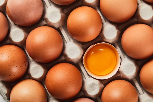 Vue du dessus de la coquille d'oeuf cassée avec jaune jaune jaune près des œufs dans la boîte en carton — Photo de stock