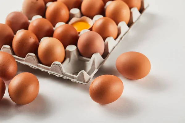 Zerbrochene Eierschale mit gelbem Eigelb in der Nähe von Eiern im Karton — Stockfoto
