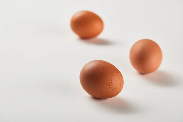 Enfoque selectivo de huevos de pollo en la superficie blanca - foto de stock