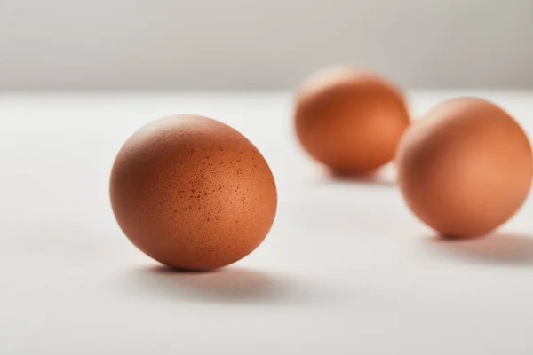 Enfoque selectivo de huevos de pollo en la superficie blanca - foto de stock