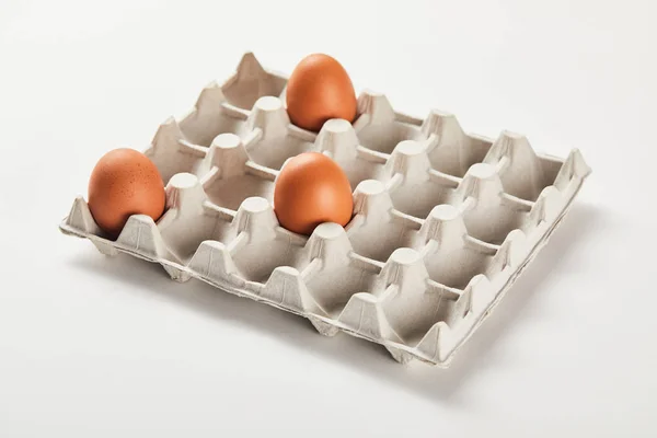 Oeufs de poulet dans une boîte en carton sur surface blanche — Photo de stock