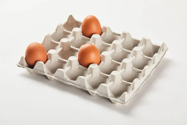 Chicken eggs in carton box on white surface — Stock Photo