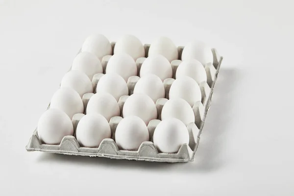 Chicken eggs in carton box on white surface — Stock Photo
