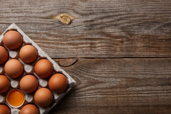 Vue du dessus des œufs de poulet dans une boîte en carton sur une table en bois — Photo de stock