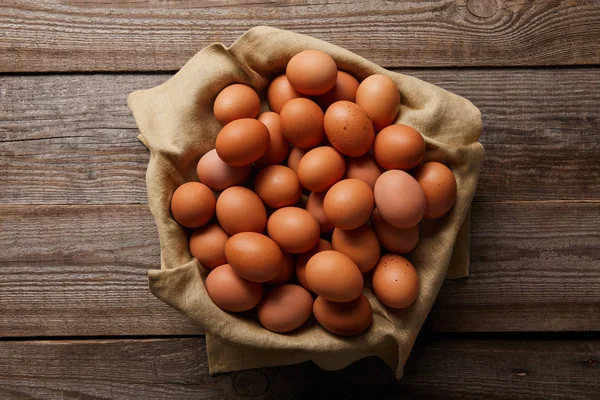 Top view of chicken eggs at cloth on wooden table — Stock Photo