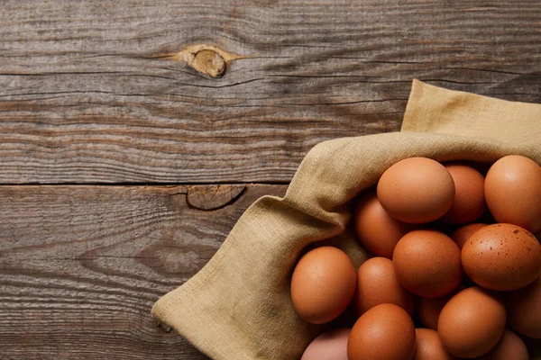 Top view of chicken eggs at cloth on wooden table — Stock Photo