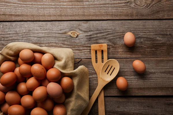 Vue du dessus des œufs de poulet sur une table en bois près des ustensiles de cuisine — Photo de stock