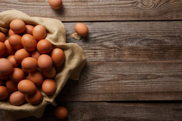 Top view of chicken eggs at cloth on wooden table — Stock Photo