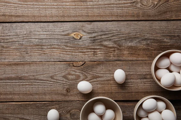 Vista dall'alto di uova di pollo in ciotole su tavolo di legno — Foto stock