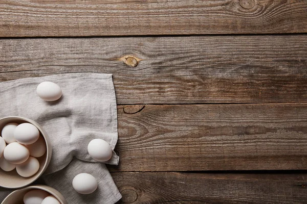 Vista dall'alto di uova di pollo in ciotole su tavolo di legno con stoffa — Foto stock