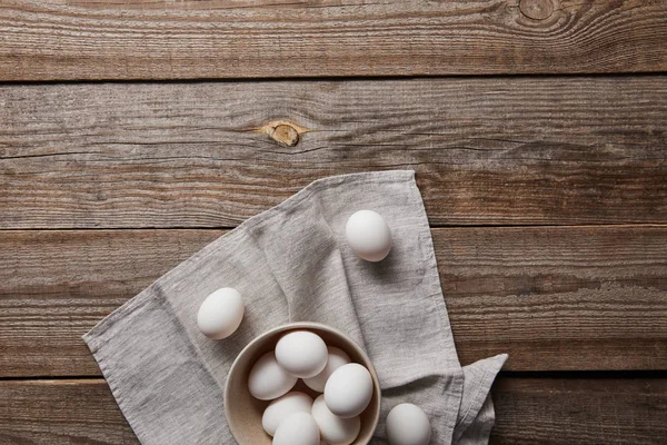 Vue du dessus des œufs de poulet dans un bol sur une table en bois avec du tissu — Photo de stock