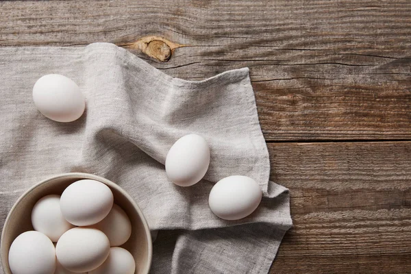 Top view of chicken eggs in bowl on wooden table with cloth — Stock Photo