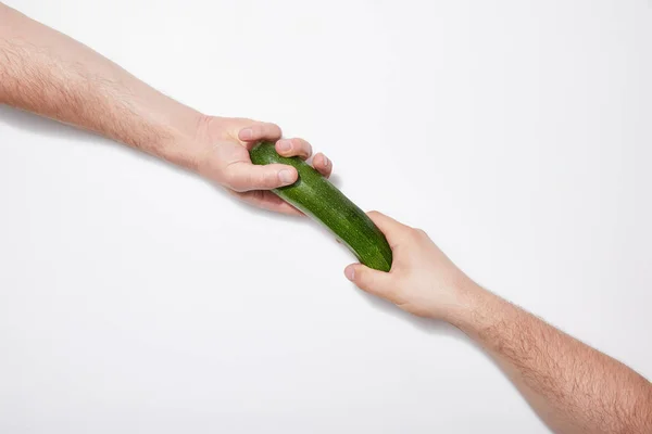 Cropped view of men sharing green zucchini on white background — Stock Photo