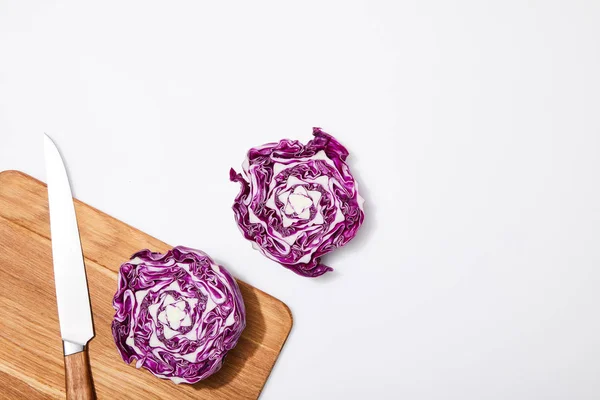 Top view of red cabbage on wooden chopping board and knife on white background — Stock Photo