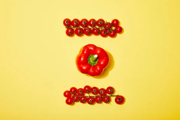 Tendido plano con tomates rojos cereza y pimentón sobre fondo amarillo - foto de stock