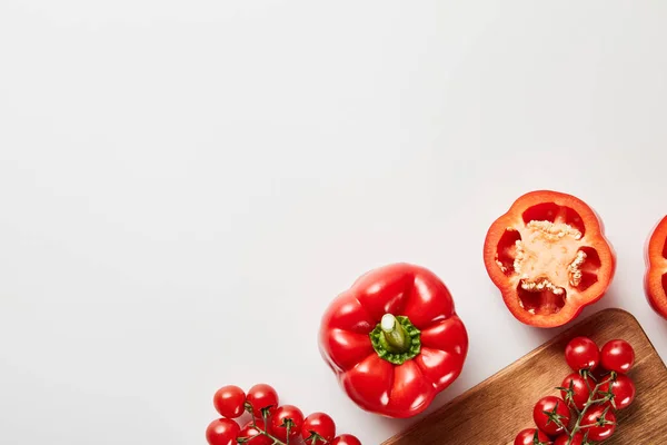 Вид зверху на червоні органічні овочі та дерев'яна дошка на білому тлі — стокове фото