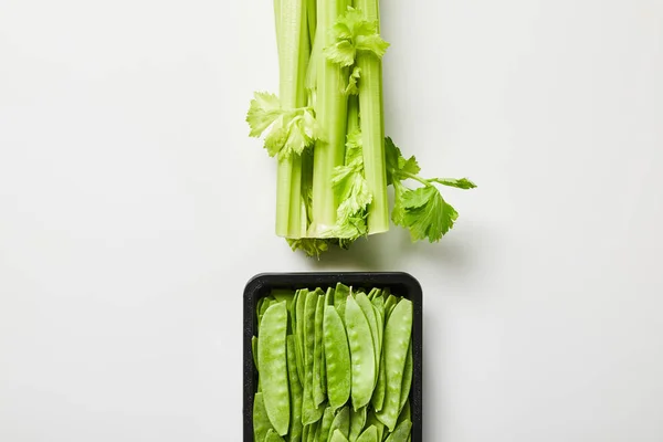 Vue du dessus du poireau et des pois biologiques verts en boîte sur fond blanc — Photo de stock