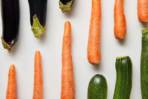 Tendido plano con zanahorias frescas, berenjenas y calabacines sobre fondo blanco - foto de stock