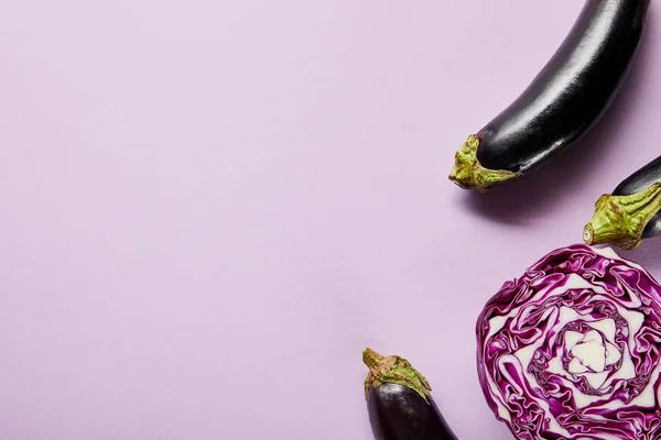 Top view of ripe eggplants and red cabbage on violet background with copy space — Stock Photo