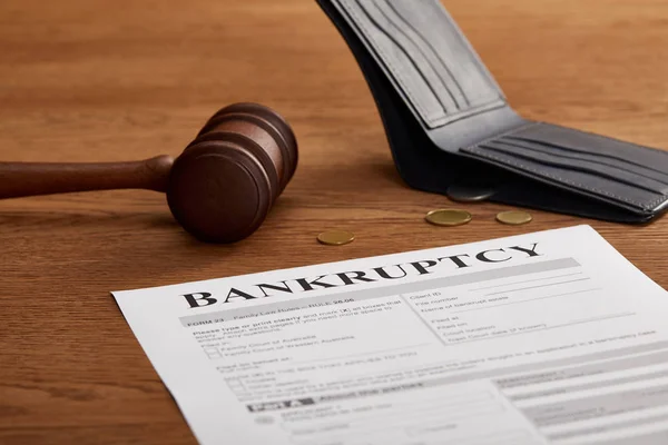 Forma de bancarrota con mazo de madera, monedas y billetera en mesa de madera marrón - foto de stock