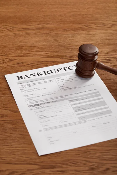 Bankruptcy form with wooden gavel on brown wooden surface — Stock Photo