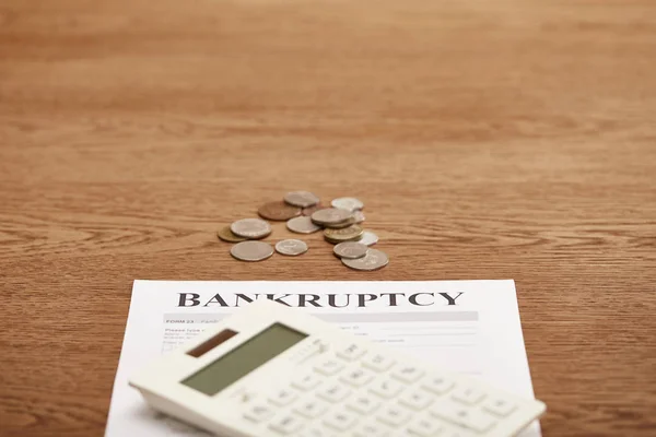 Selective focus of bankruptcy form, calculator and coins on brown wooden table with copy space — Stock Photo