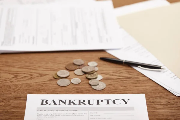 Selective focus of bankruptcy form, coins and documents on brown wooden table — Stock Photo