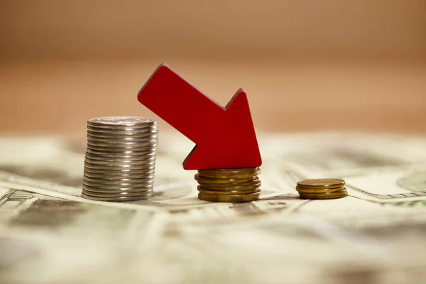 Selective focus of decreasing chart made of coins with red arrow on dollar banknotes, bankruptcy concept — Stock Photo