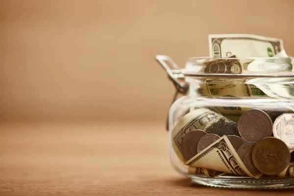 Close up view of glass jar with dollar banknotes and metal coins — Stock Photo