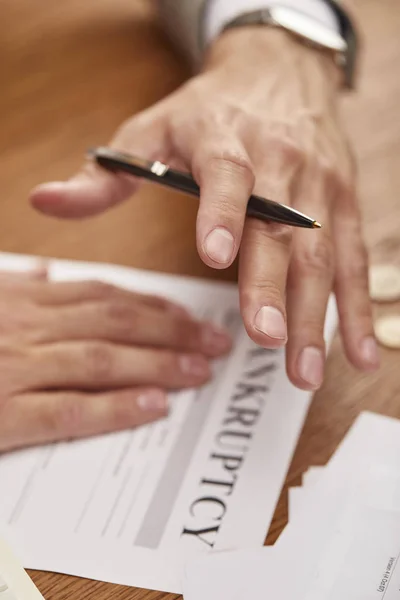 Ausgeschnittene Ansicht eines Geschäftsmannes, der am Holztisch Stift über Konkursformular hält — Stockfoto