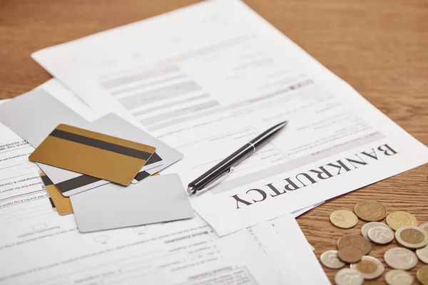 Bankruptcy form among documents, credit cards and coins on wooden table — Stock Photo