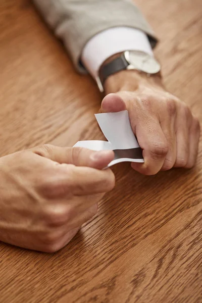 Partial view of businessman breaking credit card at wooden table — Stock Photo