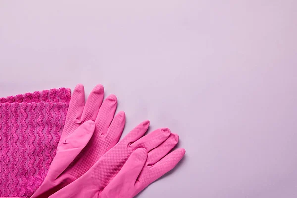Vue du dessus du chiffon rose, gants en caoutchouc sur fond violet — Photo de stock