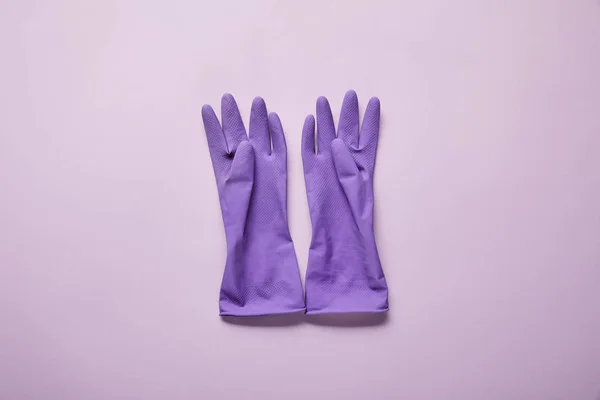 Draufsicht auf helle und bunte Gummihandschuhe auf lila Hintergrund — Stockfoto