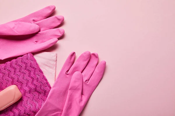 Vista superior de trapos rosados, guantes de goma y jabón sobre fondo rosa - foto de stock
