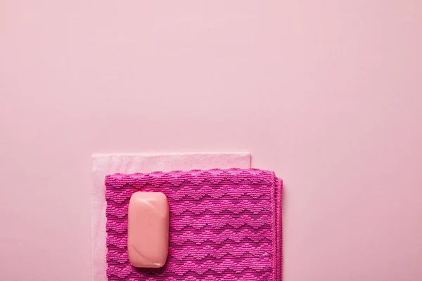 Vista superior de trapos rosados y jabón sobre fondo rosa - foto de stock