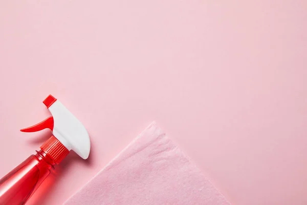 Draufsicht auf rosa Lappen und Flasche mit Spray auf rosa Hintergrund — Stockfoto