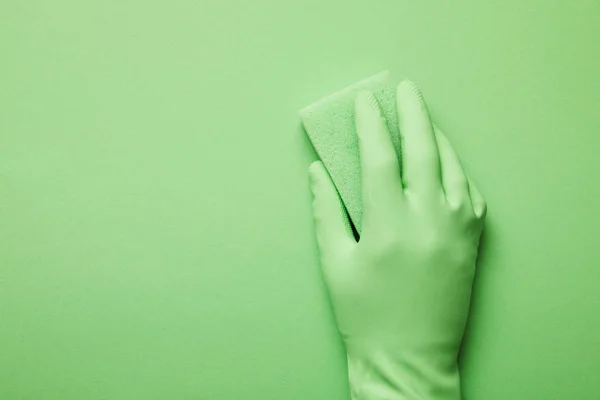 Vista recortada del hombre en guante de goma con esponja verde - foto de stock