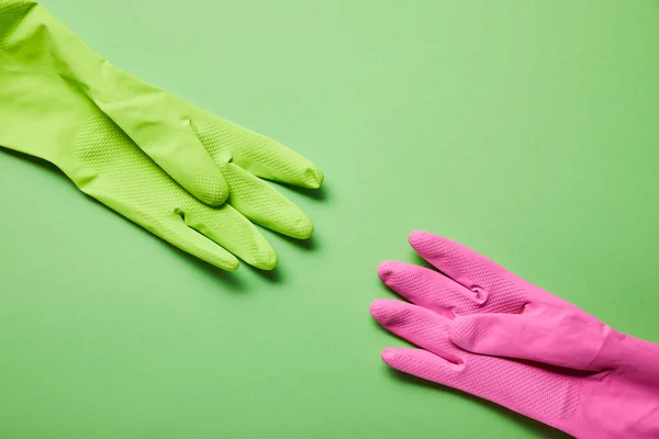 Vista superior de guantes de goma brillantes y coloridos sobre fondo verde - foto de stock