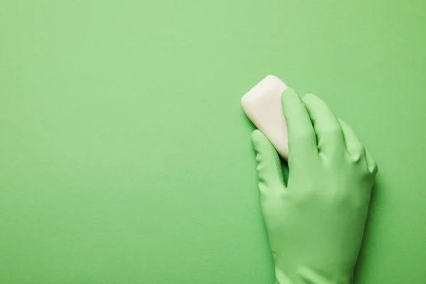 Cropped view of man in rubber glove holding white soap on green background — Stock Photo
