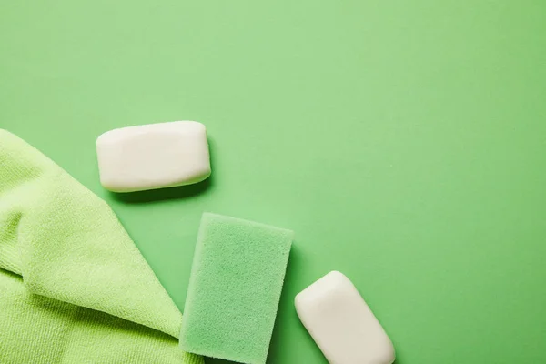 Top view of white soaps, rag and sponge on green background — Stock Photo