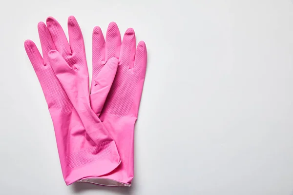Вид сверху розовых резиновых перчаток на сером фоне с копировальным пространством — стоковое фото