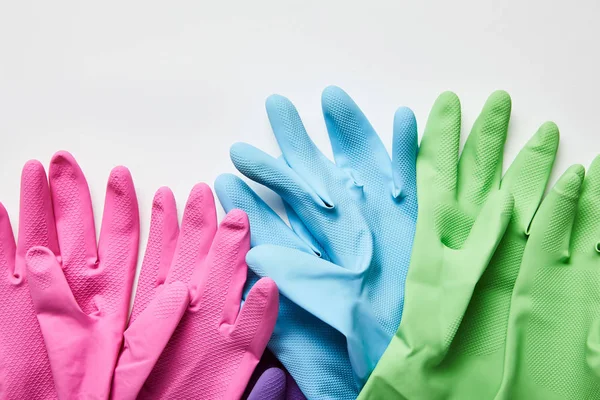 Top view of pink, green and blue rubber gloves on grey background — Stock Photo