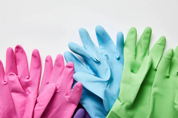 Vista superior de los guantes de goma rosa, verde y azul sobre fondo gris - foto de stock