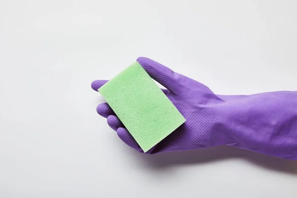 Обрезанный вид человека в фиолетовой резиновой перчатке с зеленой губкой — стоковое фото