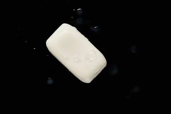 Vista superior de jabón blanco con gotas sobre fondo negro - foto de stock