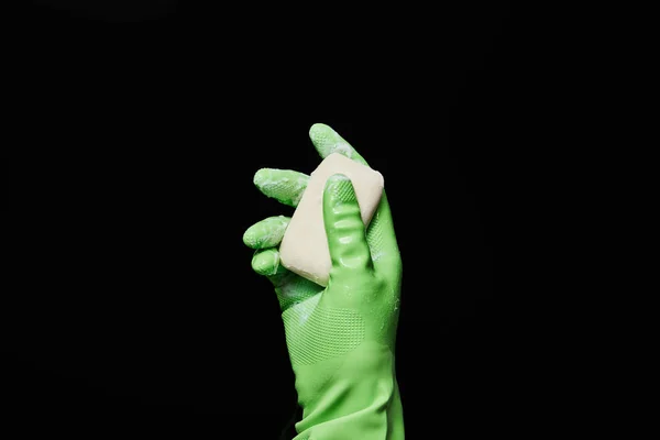 Обрезанный вид человека в зеленой резиновой перчатке с белым мылом, изолированным на черном — стоковое фото